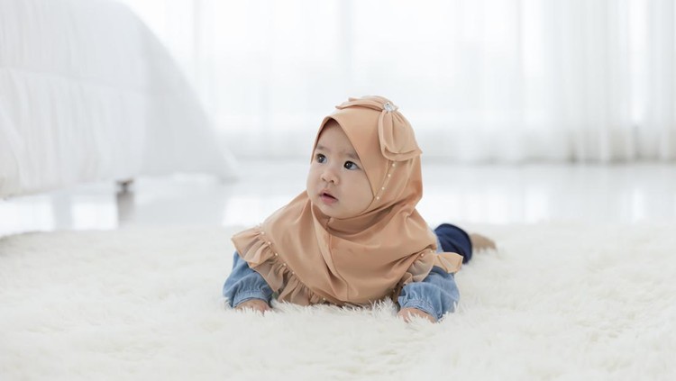 1335226017 Baby girl 6 months crawling on the floor in the bedroom. Children Asian in hijab clothing