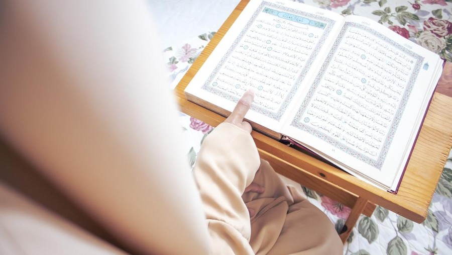 Al-Qur'an Muslim woman reading from the Quran. She was wearing a polite Abaya Muslim dress.