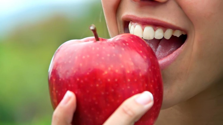 458047741 Closeup of a mouth biting a red apple