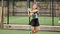 <p>Tak mau kalah, Nana Mirdad juga terlihat kece saat berlatih tenis bersama sang suami, Andrew White. Ia mengenakan baju tenis warna hitam yang dilapis dengan <em>tanktop</em> hijau. <em>Sneakers</em> hitam semakin menambah kesan <em>sporty</em> pada penampilannya. (Foto: Instagram @andrew.white._)</p>
