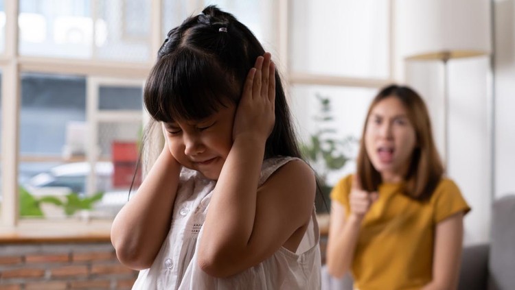 Indoor shot of young Asian girl crying and cover her ear with hands and feel sad while get scold and shout with angry from her angry mother. Child abuse that can cause a problem for children.