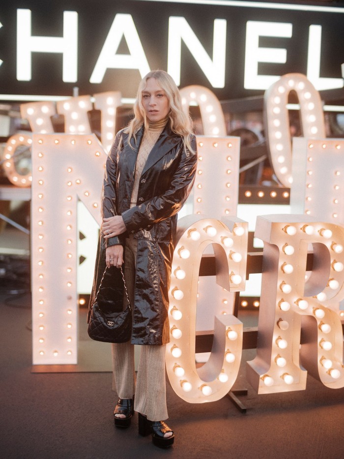 Chloe Sevigny memilih gaya yang effortless dan chic lewat kombinasi mantel hitam dan busana serba beige. Foto: Courtesy of Chanel