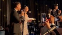 <p>Penampilan Duta di panggung resepsi membuat pasangan pengantin ikut berjoget dan menyanyi. Yakup terlihat menggandeng Jessica ketika menikmati penampilan Duta di panggung. (Foto: Instagram @jscmila)</p>