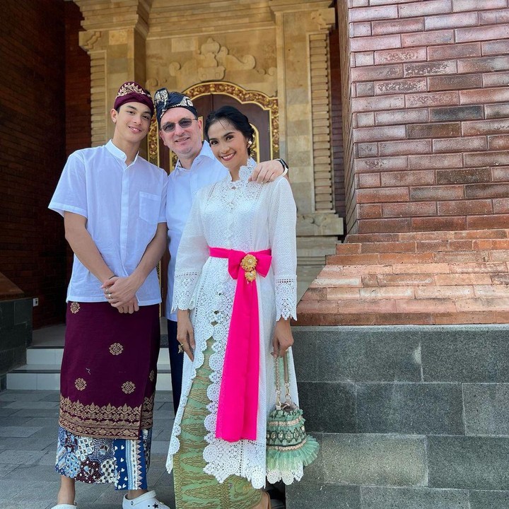 <p>Maudy juga mengikat sebuah kain berwarna merah muda di pinggangnya. Sementara itu, sang putra dan suami mengenakan udeng atau penutup kepala khas Bali. (Foto: Instagram: @maudykoesnaedi)</p>
