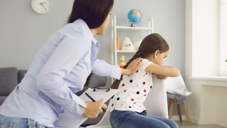 Child psychologist psychology. Woman psychologist with a clipboard helps a child with a problem in the room. Doctor psychologist reassures the patient girl in the clinic office.