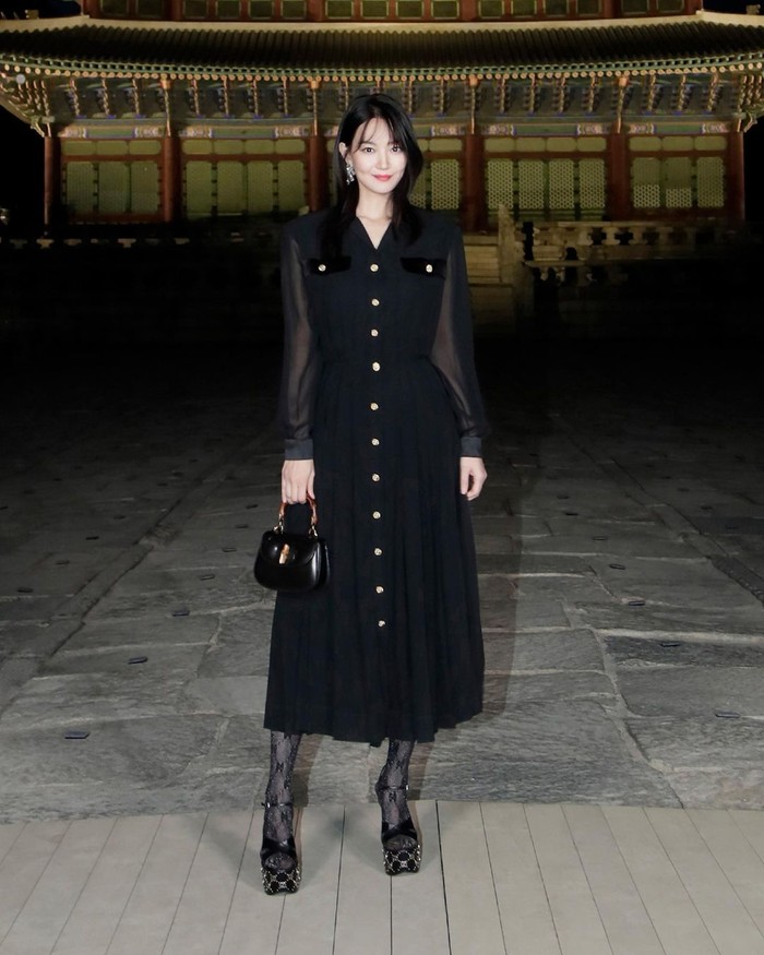 Sebelum berlibur ke Bali, Shin Min Ah hadir di acara Gucci. Ia tampil elegan mengenakan shirt dress hitam aksen kancing dengan sepatu dan tas senada. Foto: Instagram Gucci