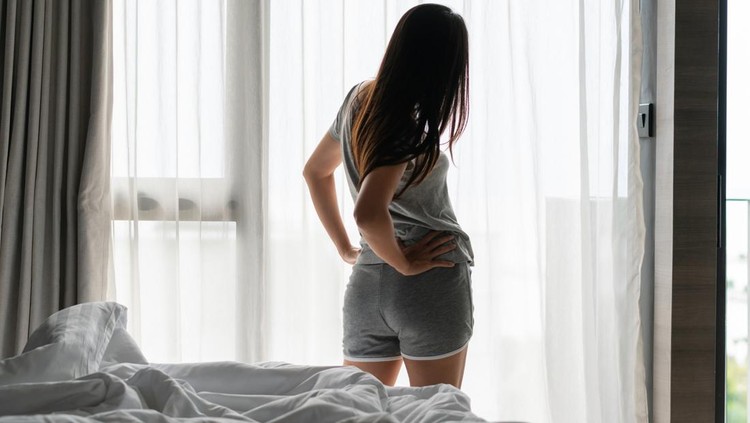 Woman suffering from back ache on the bed, healthcare and problem concept