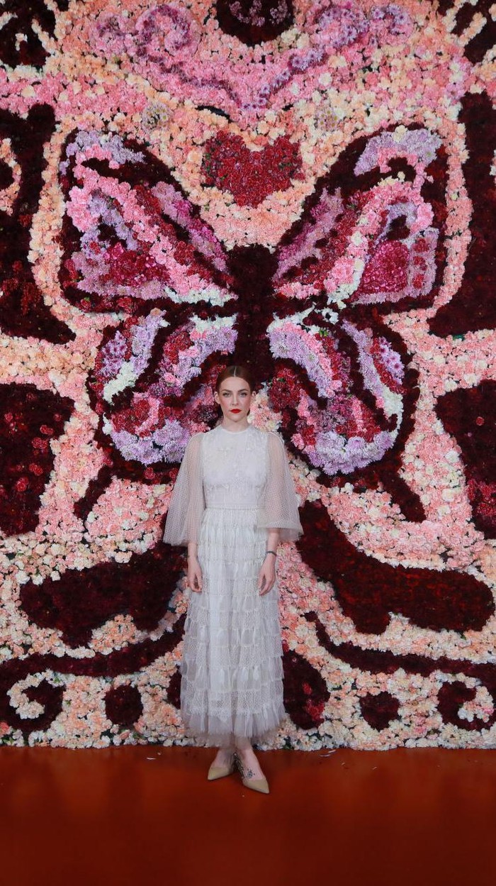 Bergaya bohemian dan laid back di serial Daisy Jones & The Six (2023), Riley Keough menampilkan versi lebih glamor dan classy di acara Dior dalam gaun putih detail bordir. Sublime! Foto: Courtesy of Dior