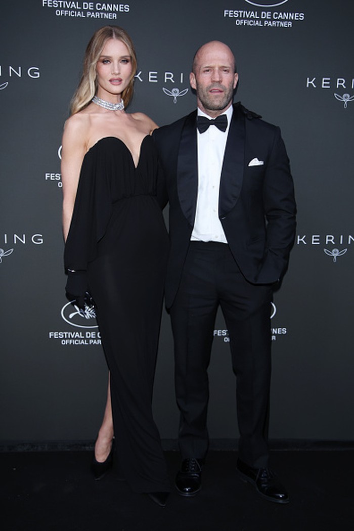 Hitam juga jadi pilihan Rosie Huntington-Whiteley yang fierce berbalut gaun Saint Laurent. Sementara Jason Statham tampil lebih klasik memakai setelan jas dan dasi kupu-kupu. Foto: Getty Images for Kering/Daniele Venturelli