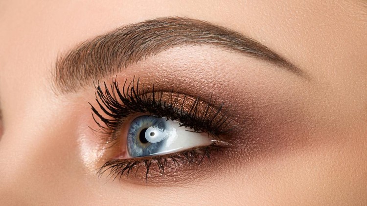 625041784 Close up of blue woman eye with beautiful brown with red and orange shades smokey eyes makeup. Modern fashion make up.