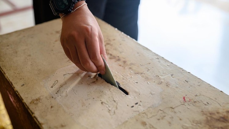 Image of Man hand donating money into charity box.