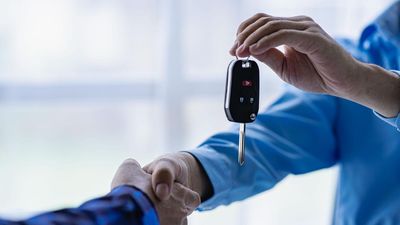 Closeup of car sale and buyer shaking hands Car salesman gives keys to buyer Close-up of car dealership business giving keys to new owner and handshake in office