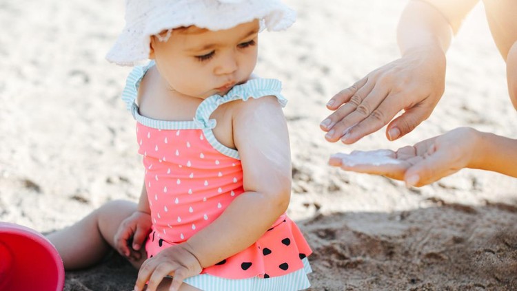 Happy laughing toddler girl having fun on sand