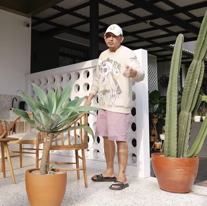 <p>Pada bagian teras rumah, pasangan ini mengusung konsep kebun yang bertolak belakang dari konsep tropis di interior rumah. "Sharen bilangnya mini California karena konsepnya seperti di padang pasir gitu, dengan tanaman yang berduri. Kita bikin panggung buat nerima tamu di sini," ucap Delon. (Foto: YouTube Sharena Delon - Party of Four)</p>
