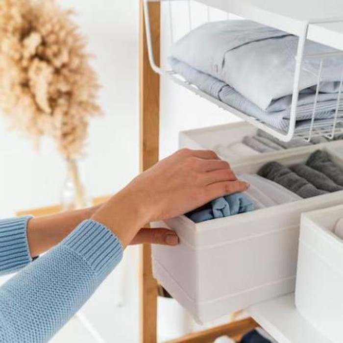 Tangan seseorang sedang merapikan baju di lemari