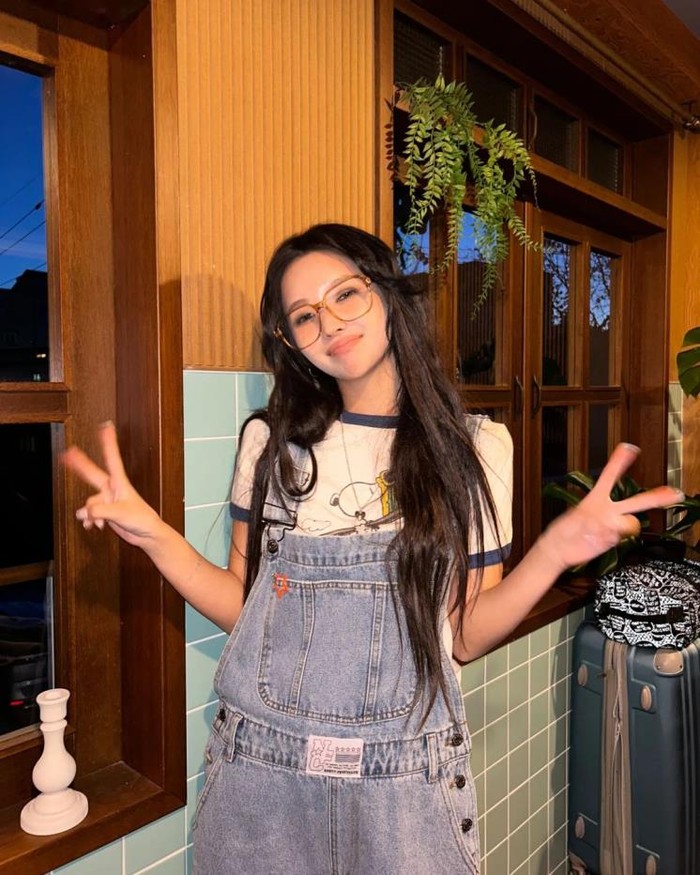 Soyeon (G)I-DLE seolah kembali ke masa lalu dengan overall jumpsuit denim wash vintage. Ia memadukan T-shirt bergaya retro dengan trim biru dan kacamata oversized yang memancarkan nuansa remaja tahun 80-an. / Foto: Elle.co.kr