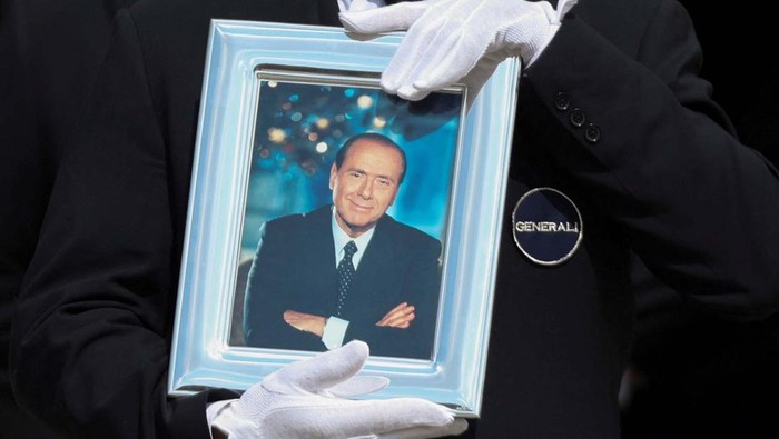 A pallbearer holds a portrait of former Italian Prime Minister Silvio Berlusconi while walking in front of the coffin during his state funeral at the Duomo Cathedral, in Milan, Italy June 14, 2023. REUTERS/Yara Nardi
