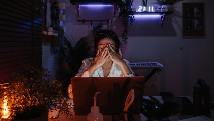 Asian woman working late and serious action on the table in front of computer monitor desktop in the room at home in the dark,