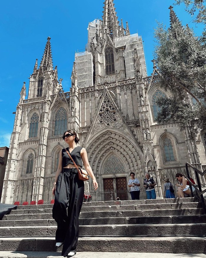 Jessica Mila berpose di depan Cathedral of Barcelona. Di tengah musim panas, ia tetap stylish pakai outfit hitam dan sling bag. /Foto: instagram.com/jscmila