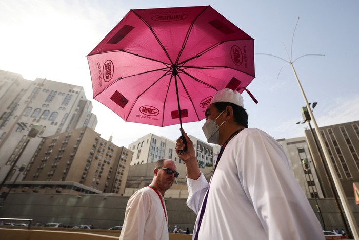 Men walk with umbrellas as people start arriving to perform the annual Haj in the Grand Mosque, in the holy city of Mecca, Saudi Arabia, June 24, 2023. REUTERS/Mohamed Abd El Ghany