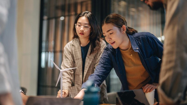 1443559562 Business people is talking about new project in the meeting room. Team is standing around a table and listening their manager carefully.