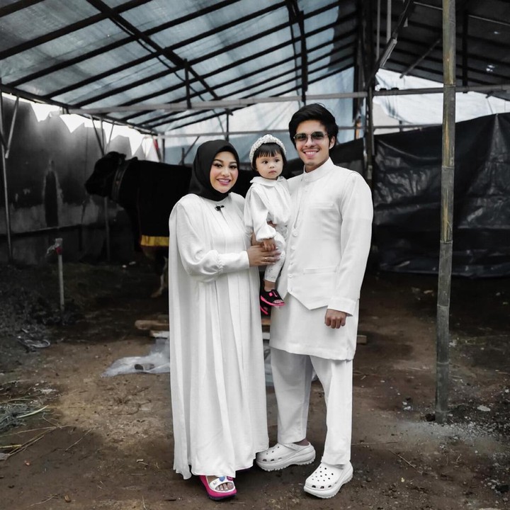 <p>Aurel Hermansyah kompak mengenakan pakaian serba putih dengan suaminya Atta Halilintar, dan putrinya Ameena. Aurel dan Atta membagikan momen bersama kebersaman mereka dengan sang putri di media sosial. Ketiganya tampak berpose di dekat hewan kurban. (Foto: Instagram @aurelie.hermansyah)</p>