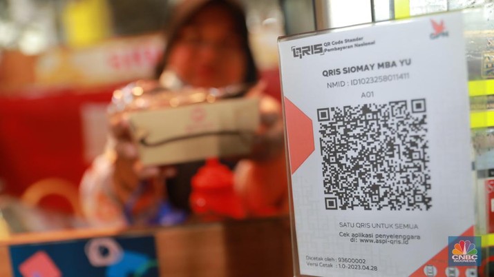 Pembeli melakukan transkasi pembayaran qris di Pasar Santa, Jakarta, Senin, (3/7). (CNBC Indonesia/Muhammad Sabki)