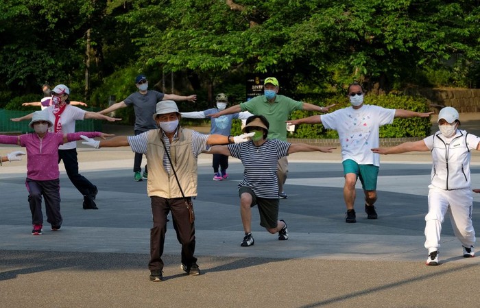 This picture taken on May 25, 2021 shows people taking part in a morning 'radio taiso' exercise at a park in Tokyo. - It might not make the cut for Olympians at Tokyo 2020, but each day in Japan's parks, schools and offices millions perform the country's most popular stretching routine: radio taiso.
 - TO GO WITH Oly-2020-2021-Japan-health-exercise-virus-taiso,FOCUS by Ayaka McGill and Katie Forster (Photo by Kazuhiro NOGI / AFP) / TO GO WITH Oly-2020-2021-Japan-health-exercise-virus-taiso,FOCUS by Ayaka McGill and Katie Forster (Photo by KAZUHIRO NOGI/AFP via Getty Images)