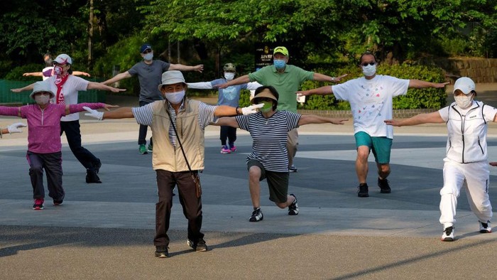 This picture taken on May 25, 2021 shows people taking part in a morning 'radio taiso' exercise at a park in Tokyo. - It might not make the cut for Olympians at Tokyo 2020, but each day in Japan's parks, schools and offices millions perform the country's most popular stretching routine: radio taiso.
 - TO GO WITH Oly-2020-2021-Japan-health-exercise-virus-taiso,FOCUS by Ayaka McGill and Katie Forster (Photo by Kazuhiro NOGI / AFP) / TO GO WITH Oly-2020-2021-Japan-health-exercise-virus-taiso,FOCUS by Ayaka McGill and Katie Forster (Photo by KAZUHIRO NOGI/AFP via Getty Images)