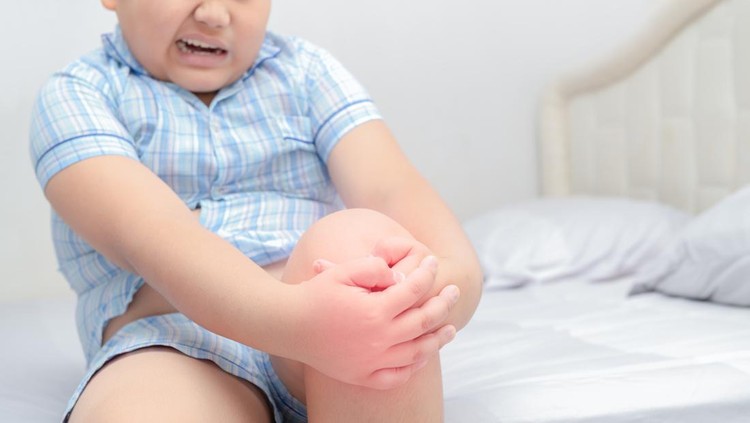 Ilustrasi Kanker Tulang pada Anak Obese fat boy suffering from knee pain and sit on bed, Healthy problem