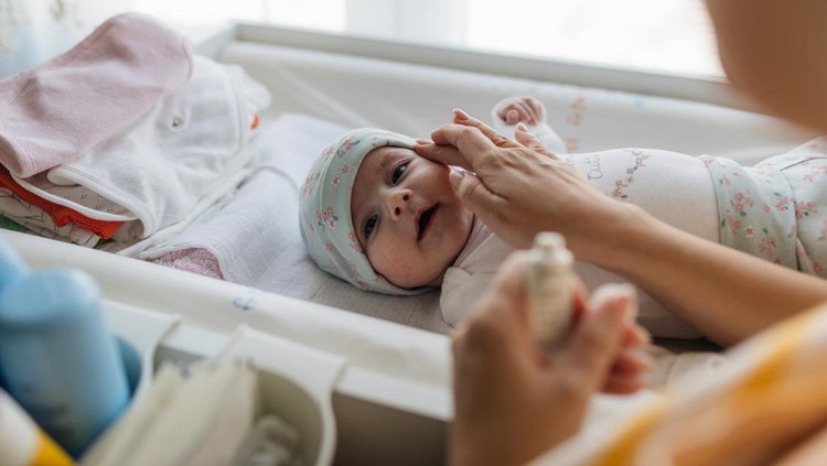 Mother applying baby skin care cream on her little girl