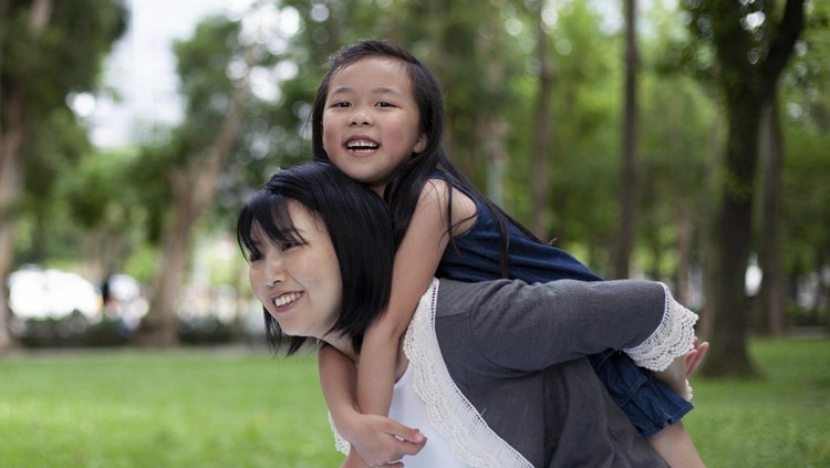 Asian little girl on a piggy back ride with her mother in park Taipei