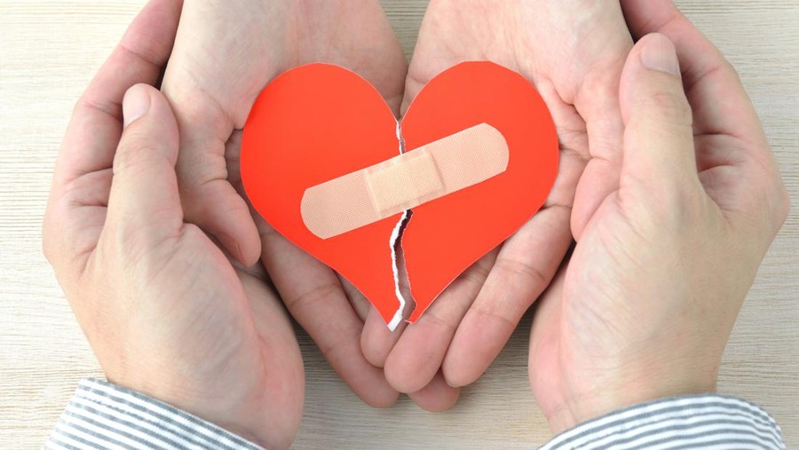 1250915872 Couple's hands having broken heart with adhesive plaster