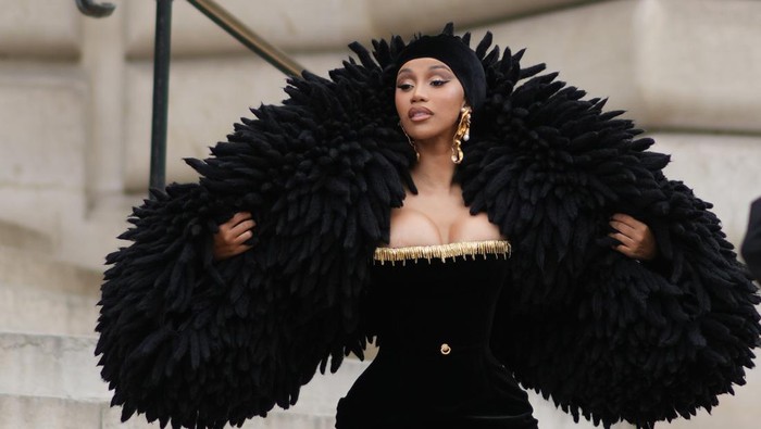 PARIS, FRANCE - JULY 03: Cardi B wears  a black velvet scarf as a hat from Schiaparelli, gold large ears and white pearls pendant earrings from Schiaparelli, a black velvet with embroidered gold metallic shoulder-off borders / long tube dress from Schiaparelli, gold large bracelets from Schiaparelli, pumps heels shoes , a black fluffy oversized puffy jacket from Schiaparelli, outside Schiaparelli, during the Haute Couture Fall/Winter 2023/2024 as part of  Paris Fashion Week on July 03, 2023 in Paris, France. (Photo by Edward Berthelot/Getty Images)