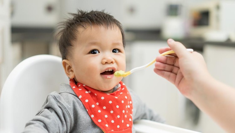 Asian baby boy eating blend food on a high chair