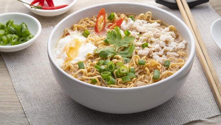 Instant noodle soup with minced pork and boiled egg in white bowl on wood table