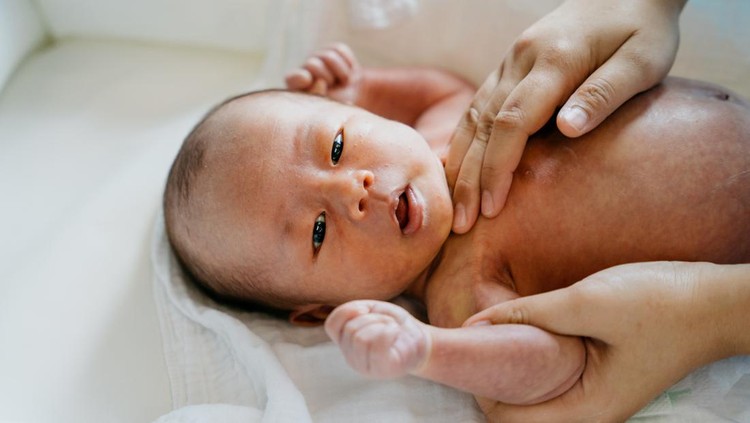 Image of a mother applying baby cream on her newborn baby after bathing. Mother massaging her newborn baby.