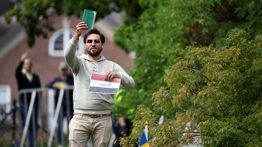 Salwan Momika, mengangkat buku yang disebutnya Al-Qur'an dan memegang kertas bendera Irak dalam aksi protes terbaru di luar Kedutaan Irak di Stockholm pada Kamis (20/7) waktu setempat Protestor Salwan Momika holds up the Muslim holy book and a sheet of paper showing the flag of Iraq during a protest outside the Iraqi Embassy in Stockholm, Sweden, on July 20, 2023. Iraq warned Sweden on July 20, 2023 that it would cut diplomatic relations if a Koran-burning protest is allowed to go ahead in Stockholm, after protesters stormed and torched the Swedish embassy in Baghdad overnight. (Photo by Oscar Olsson / TT News Agency / AFP) / Sweden OUT