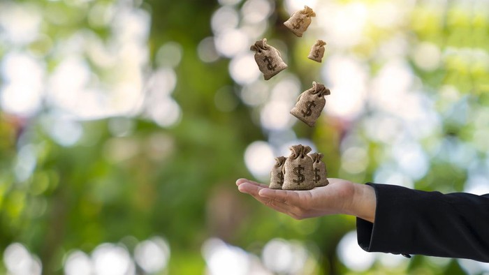 Woman hand holding money bag and blur green nature background finance concept, future planning for investment loans.