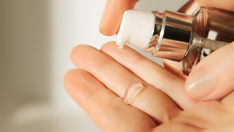 1389146537 Push dispenser liquid facial fluid gel squeezed out to hand. Cosmetologist pours clear cleansing moisturizing hyaluronic serum acid. Cosmetic concept.