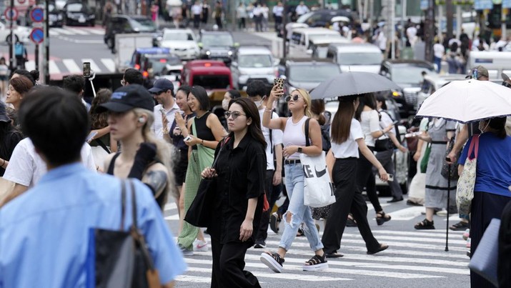 Orang-orang berjalan melintasi penyeberangan pejalan kaki di distrik Shibuya dalam cuaca panas dan lembab Kamis, 13 Juli 2023, di Tokyo. (AP Photo/Eugene Hoshiko)