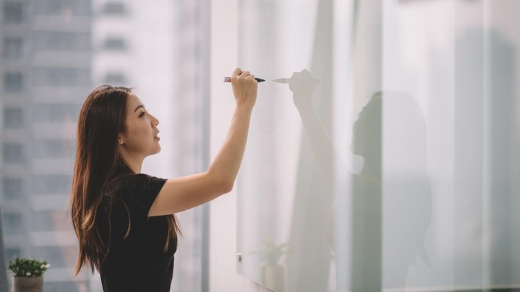 an asian chinese female writing on white board with her marker pen during conference meeting in office conference room