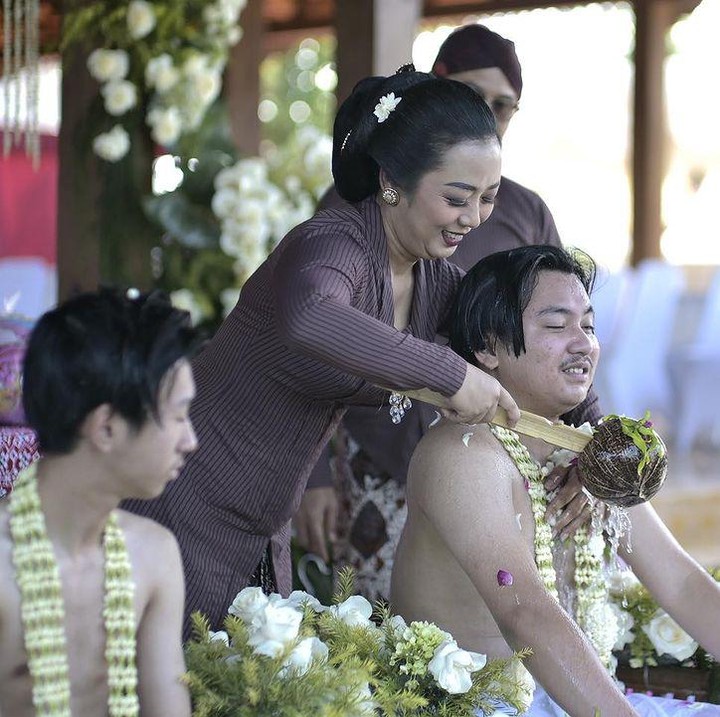 <p>Senyum bahagia terlihat di wajah Soimah saat melakukan proses siraman dalam acara ruwatan pada putra pertamanya, Aksa Uyun Dananjaya. Tepat di sebelah Aksa, sang adik Diksa tampak sedang menunggu giliran. (Foto: Instagram @showimah)</p>