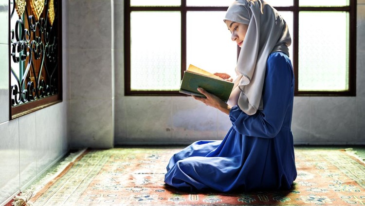 Beautiful Asian young Muslim woman sit on the floor in her house and praying for a holy god - Allah in Islam believe.