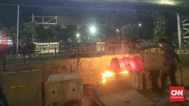 Massa buruh yang melakukan unjuk rasa di kawasan Patung Kuda di Jalan Medan Merdeka Barat mulai menaiki pembatas beton dan kawat berduri.