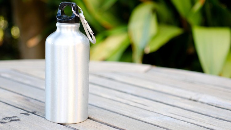 Reusable water bottle on a wooden table outdoors