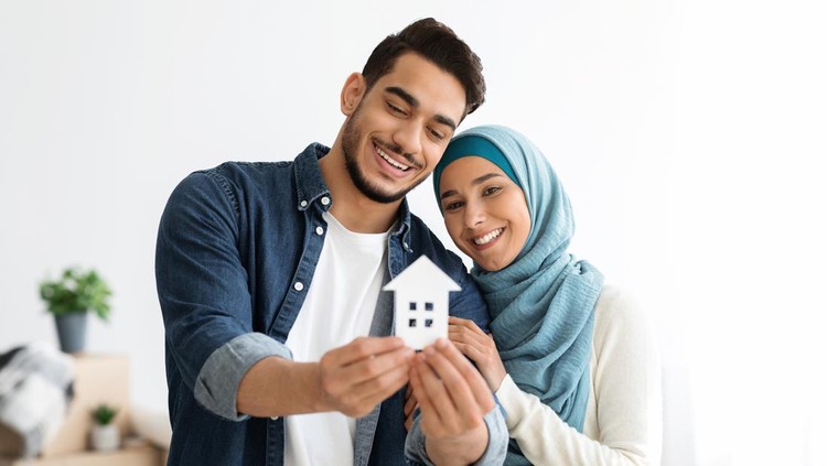 1319039993 Young loving muslim couple middle eastern man and woman in hijab showing paper house at camera and smiling, real estate and relocation concept, copy space. Muslim family moving
