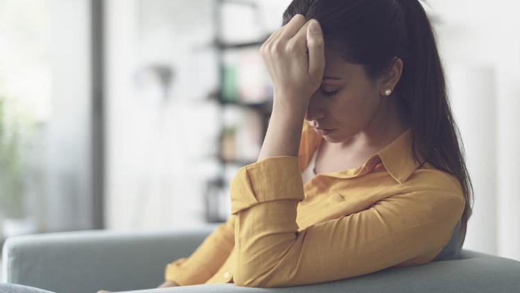 1319744279 Depressed young woman sitting in the living room at home, she is feeling hopeless and sad