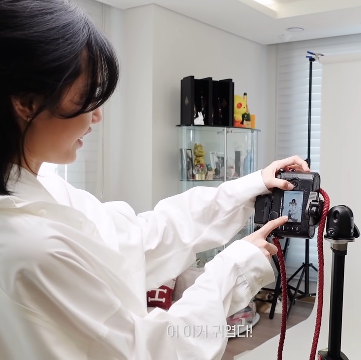 <p>Pelantun lagu <em>Money</em> itu menyulap ruangan utama menjadi studio foto sederhana. Ia memasang <em>background</em> berwarna putih sebagai latar foto. (Foto: YouTube Lilifilm Official)</p>
