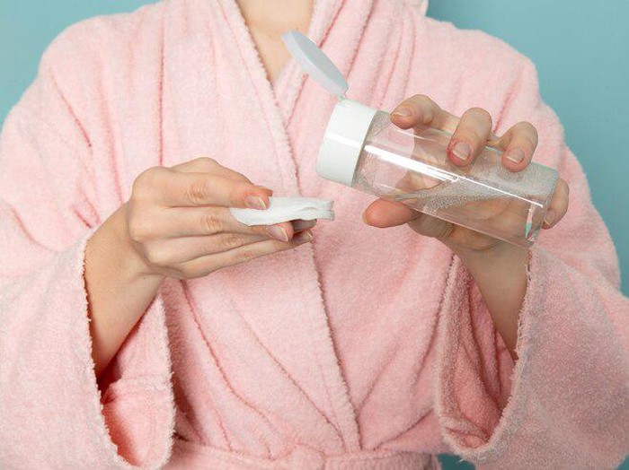 Foto seorang perempuan dengan botol toner dan kapas.